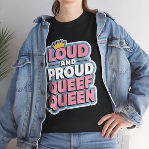 May include: Black t-shirt with a graphic design that says "Loud and Proud Queef Queen" in pink, blue, and yellow lettering.
