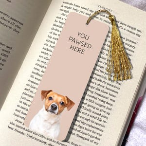 Op de afbeelding: Een roze en witte bladwijzer met een illustratie van een bruine en witte hond. De bladwijzer heeft de tekst "You Pawsed Here" in zwarte letters.