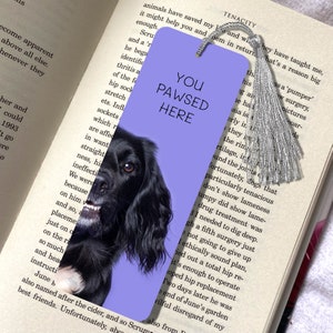 Könnte beinhalten: Ein violetter Lesezeichen mit einem Schwarzweißbild eines Hundekopfes. Das Lesezeichen trägt den Text "You Pawsed Here" in weißen Buchstaben.