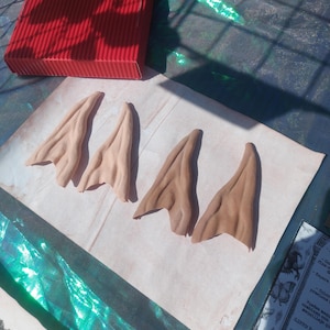 Puede incluir: Dos pares de orejas de elfo, un par es de color marrón claro y el otro par es de color marrón oscuro. Las orejas están hechas de un material suave y flexible y están diseñadas para ser usadas como un accesorio de disfraz.