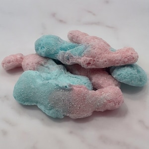 Könnte beinhalten: Ein Haufen rosa und blauer Süßigkeiten in Form von Hasen. Die Süßigkeiten sind mit einer weißen Zuckerglasur überzogen.