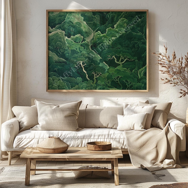 Cozy living room with a neutral-toned sofa, cushions, and a beige blanket. Above, a large framed artwork depicts a lush green forest landscape.