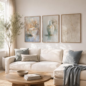 May include: A living room with three framed watercolour art prints. The prints show a bowl, a vase, and an abstract design with gold accents. A white sectional sofa with blue cushions and a wooden coffee table complete the decor.