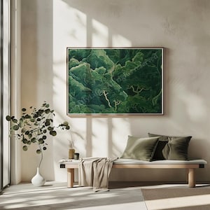 A serene, minimalist living space with a large, framed green forest painting on a light wall. Sunlit bench with green cushions, small plant in white vase.
