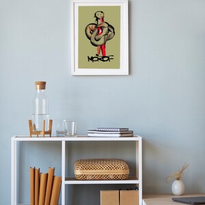May include: A white framed print of a digital illustration of a person in a green and red outfit with the word "MOFOF" written below the figure.