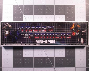 May include: A rectangular box with the Transformers logo in red, white, and blue. The text "MINI-SPIES" is below the logo. The box also includes images of Transformers characters and the text "MORE THAN MEETS THE EYE".