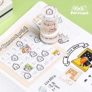 May include: A white and brown stamp with a cartoon poop emoji design. The stamp is labeled "Stamp" and "Fun for Every Day" in black text. The stamp is on a white background with a calendar grid and other stamps.