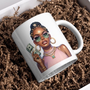 May include: White ceramic mug with a colorful illustration of a woman wearing sunglasses and holding cash. She is wearing a pink top and gold jewelry.