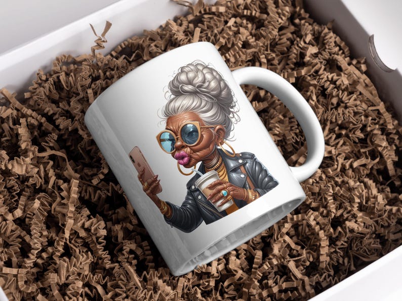 Pode incluir: Caneca de cer&acirc;mica branca com uma ilustra&ccedil;&atilde;o colorida de uma mulher com cabelo grisalho, &oacute;culos de sol e uma jaqueta de couro. Ela est&aacute; segurando um smartphone em uma m&atilde;o e uma x&iacute;cara de caf&eacute; na outra.