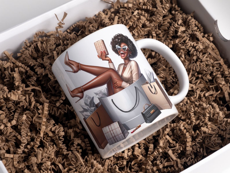 May include: White ceramic mug with a colorful illustration of a woman sitting in a shopping bag with multiple shopping bags around her. The woman is wearing sunglasses and a white top.
