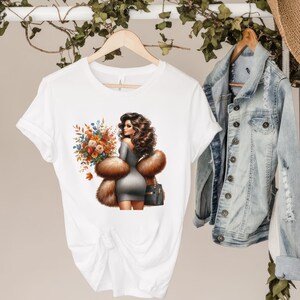 Pu&ograve; includere: Maglietta bianca con una grafica di una donna con pelliccia marrone e un mazzo di fiori.