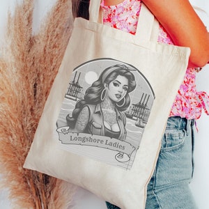 Könnte beinhalten: Eine weiße Canvas-Tragetasche mit einem schwarz-weißen Grafikdesign einer tätowierten Frau und dem Text "Longshore Ladies".