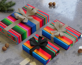 Puede incluir: Tres cajas de regalo rectangulares envueltas en papel a rayas de colores con lazos beige y negros. Las cajas están dispuestas sobre una superficie gris con elementos decorativos.