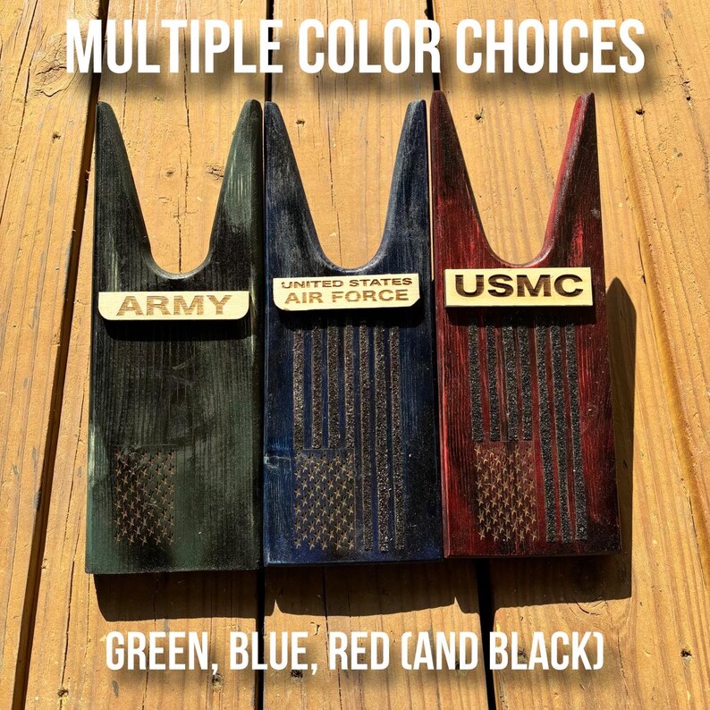 May include: Three wooden boot jacks with American flag designs. The boot jacks are painted in green, blue, and red. The boot jacks are labeled "Army", "United States Air Force", and "USMC".