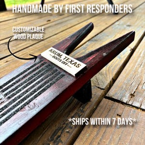 May include: A wooden boot jack with a red stain and black rubber strips. A wooden plaque with the text "KRUM, TEXAS -BOOTS OFF- " is attached to the boot jack.