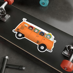 May include: A cartoon illustration of a bright orange van with the word "Juice" on the side. Five cartoon characters are inside the van, looking out the windows. The van has mud splatters on the side.