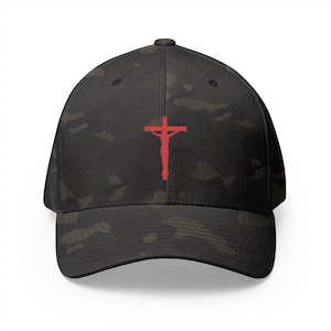 Puede incluir: Una gorra de béisbol de camuflaje negro con una cruz roja bordada en la parte delantera.