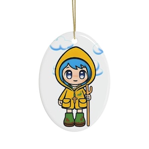 Könnte beinhalten: Ein Keramik-Weihnachtsornament mit einer Zeichentrickfigur eines Mädchens, das einen gelben Regenmantel, blaue Haare und grüne Stiefel trägt. Sie hält einen Stock mit einer Gabel am Ende. Der Hintergrund ist weiß mit blauen Wolken.