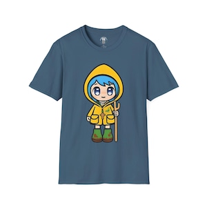 Könnte beinhalten: Ein blaues T-Shirt mit einer Cartoon-Illustration eines Mädchens, das einen gelben Regenmantel trägt und eine Heugabel hält. Das Mädchen hat blaue Augen und blaue Haare.