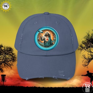 Puede incluir: Una gorra de béisbol azul desgastada con un gráfico circular de Jesús sosteniendo un frisbee. El gráfico tiene un esquema de color azul, blanco y naranja.