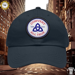 May include: A navy blue baseball cap with a white, red, and blue patch that says "CONVERT CATHOLIC TRADITION IS ALL TRUE" with a triquetra symbol in the center.