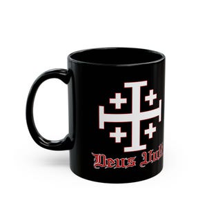 Pode incluir: Caneca de cerâmica preta com uma cruz branca com quatro cruzes menores dentro. O texto "Deus Vult" está impresso em vermelho abaixo da cruz.
