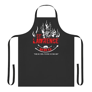 May include: Black BBQ apron with white text that reads "St. Lawrence BBQ" with flames and a pig graphic. The text below the graphic reads "Turn me over, I'm done on this side."