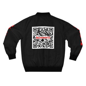 May include: Black bomber jacket with red text and a white QR code on the back. The text reads "Sacrament".