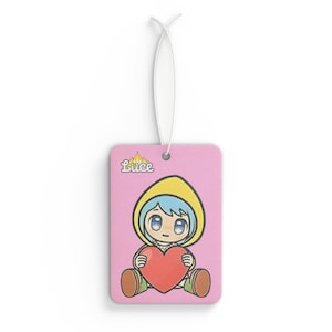 May include: Pink car air freshener with a cartoon character holding a red heart. The character is wearing a yellow hooded jacket and has blue hair. The text "Luce" is printed in the top left corner.