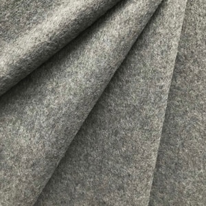 May include: A close-up of a gray felt fabric. The fabric has a soft, fuzzy texture.