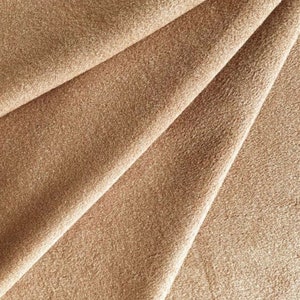 May include: Close-up of a soft, brown fabric with a textured surface. The fabric is folded in a way that shows the texture and color.