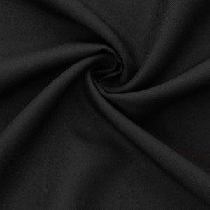 May include: Black fabric with a smooth, slightly textured surface. The fabric is folded and draped, showing its soft and flexible nature.