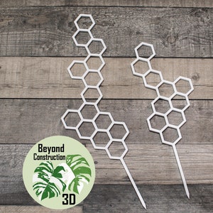May include: Two white plastic plant supports shaped like honeycombs. The supports are on a wooden background. The text "Beyond Construction 3D" is on a green circle with a white monstera leaf.