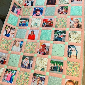 Op de afbeelding: Een gepersonaliseerde quilt met een patchwork-ontwerp. Het heeft talrijke fotovierkanten, omgeven door roze randen en afgewisseld met lichtblauwe vierkanten en stof met bloemenpatroon. De foto's tonen verschillende mensen en scènes, waardoor een aangepast textiel ontstaat.
