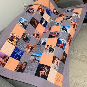 May include: A handmade patchwork quilt featuring a collection of photographs. The quilt is composed of squares in shades of peach, grey, and patterned fabric. The quilt is bordered with a solid grey fabric and is draped over a grey armchair.