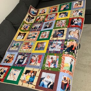 May include: A patchwork quilt with multiple framed photographs. The quilt uses a variety of fabric squares in colours such as green, yellow, red, and blue, with patterned borders. The photographs show people in different settings.