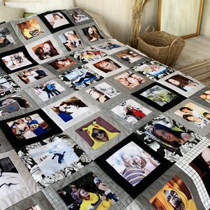 Op de afbeelding: Een gepersonaliseerde fotoquilt met een patchwork-ontwerp. De quilt bestaat uit talrijke vierkante panelen, elk met een andere foto. De panelen zijn omlijst in zwart en grijs, met accenten van patroonstof. De quilt ligt op een bed.