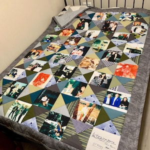 May include: A handmade quilt with a patchwork design featuring photographs. The quilt uses triangles in green, blue, and grey, forming a geometric pattern. The photos show people in different settings. The quilt is on a grey bed.