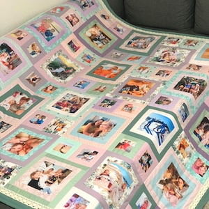 Op de afbeelding: Een gepersonaliseerde fotodeken met een patchwork-ontwerp met talrijke vierkante fotoblokken. De deken toont een verscheidenheid aan familiefoto's in pastelkleurige vierkanten, omzoomd door groene, lavendelkleurige en roze stoffen. De deken is afgewerkt met een witte kanten rand.