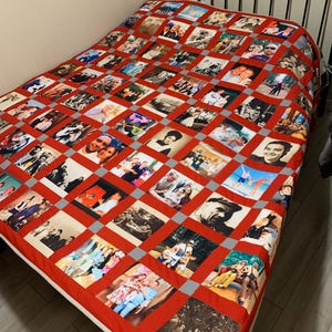 May include: A personalized quilt featuring a collage of photographs. The quilt has a red background with a grid pattern, each square containing a different photo. The edges are finished with a white border. The photos appear to be of various people and events.