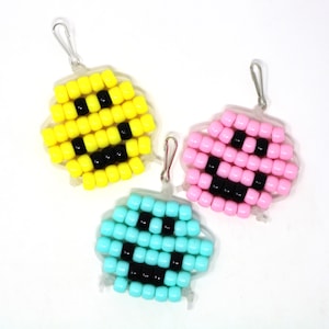 May include: Three beaded smiley face keychains. One is yellow, one is pink, and one is light blue.
