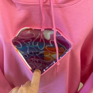 May include: Pink hoodie with a heart-shaped opening revealing a colourful fleece lining.
