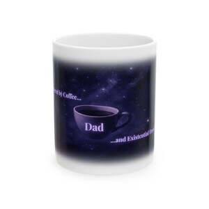 May include: White ceramic coffee mug with a dark blue and purple galaxy design. The mug features a coffee cup graphic with the word "Dad" and the phrases "fueled by Coffee..." and "...and Existential Dread".