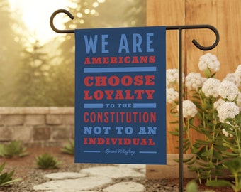 May include: A blue garden flag with white text that reads "We are Americans Choose Loyalty to the Constitution Not to an Individual - Oprah Winfrey".
