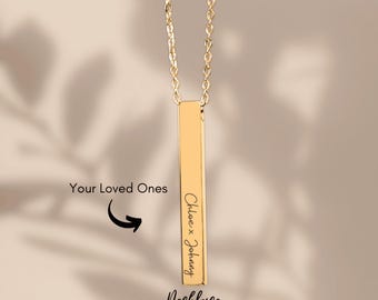 May include: A gold-colored bar necklace with a delicate chain. The bar is engraved with the names "Chloe x Johnny" in a cursive font. The text "Necklace" and "Your Loved Ones" are also visible.