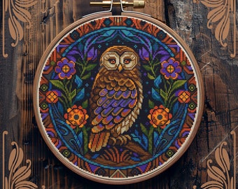 May include: Counted cross-stitch pattern of an owl in a circular frame with floral designs. The owl is brown with purple and orange accents. The background is dark blue with a star pattern. The pattern is by StitchingLand.
