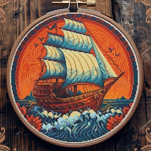 Könnte beinhalten: Gezähltes Kreuzstichmuster eines Schiffes, das auf einem blauen und orangefarbenen Meer mit einem Sonnenuntergang im Hintergrund segelt. Das Muster ist in einem Holzreifen gerahmt.