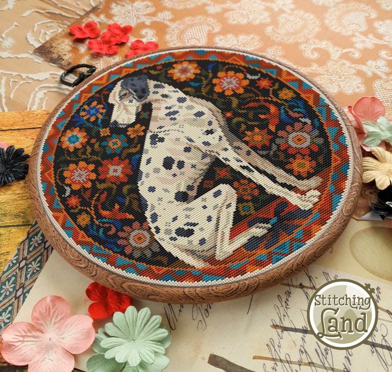 May include: A circular embroidery hoop with a colorful floral design and a white and black Dalmatian dog sitting in the center. The hoop is made of wood and has a brown finish.