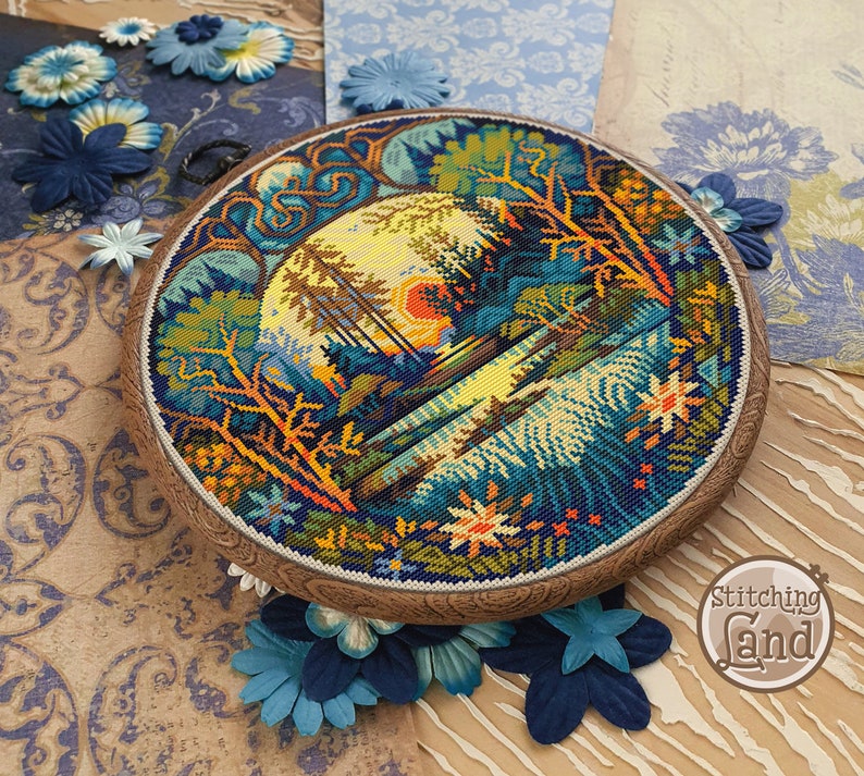 May include: A circular cross-stitch embroidery depicting a colorful landscape with trees, water, and a sunset. The embroidery is framed in a wooden hoop with a decorative edge. The text "Stitching Land" is visible in the lower right corner.