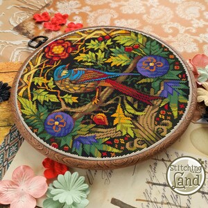 May include: A colorful cross-stitch embroidery of a bird perched on a branch surrounded by flowers and leaves. The embroidery is framed in a wooden hoop.